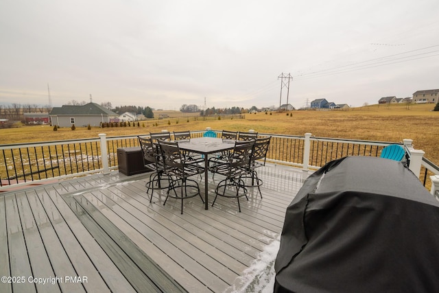 wooden deck with grilling area, a rural view, outdoor dining area, and a yard