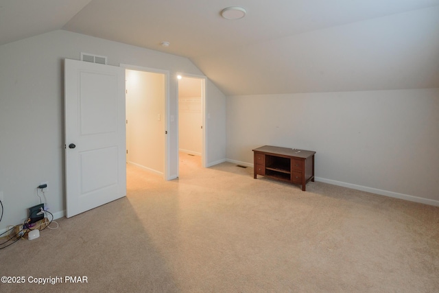 additional living space with visible vents, light colored carpet, baseboards, and vaulted ceiling