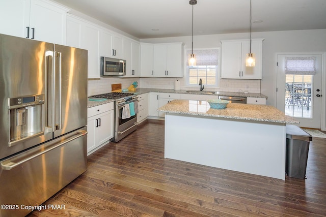 kitchen featuring a sink, backsplash, a center island, appliances with stainless steel finishes, and dark wood-style flooring