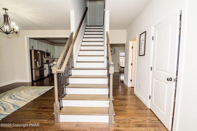 staircase featuring an inviting chandelier and wood-type flooring