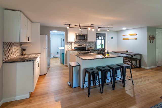 115 Squaw Trl, Pocono Lake, PA 18347 - kitchen featuring appliances with stainless steel finishes, dark countertops, a breakfast bar area, decorative backsplash, and light wood finished floors