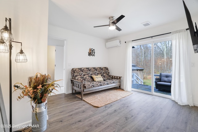 sitting room featuring hardwood / wood-style floors, ceiling fan, and a wall unit AC