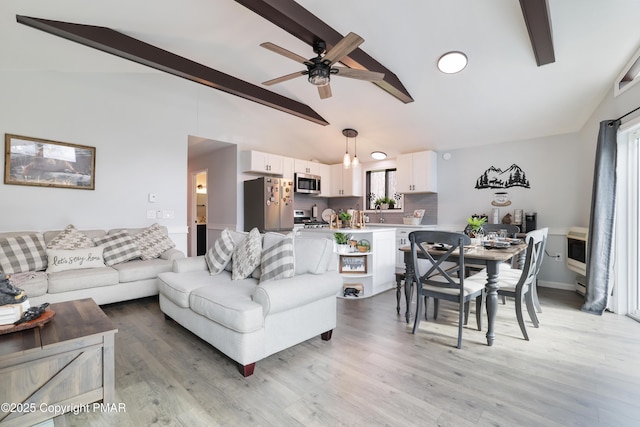 living room featuring ceiling fan, light hardwood / wood-style flooring, and vaulted ceiling with beams