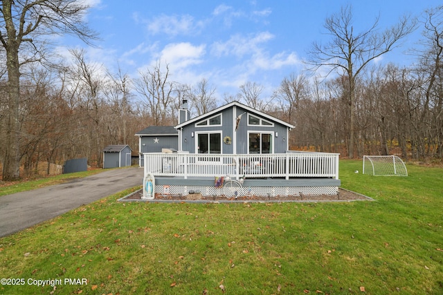 view of front facade with a deck, a storage shed, and a front yard