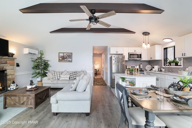 kitchen with white cabinetry, a wall unit AC, lofted ceiling with beams, appliances with stainless steel finishes, and pendant lighting