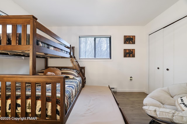 bedroom with a baseboard heating unit, dark hardwood / wood-style floors, and a closet