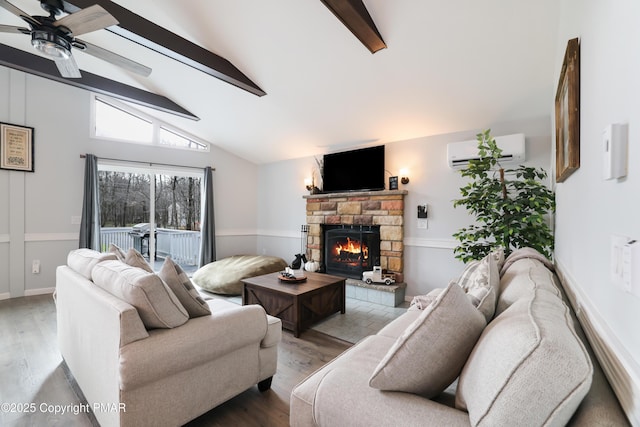 living room with vaulted ceiling with beams, light wood-type flooring, a wall mounted air conditioner, ceiling fan, and a fireplace