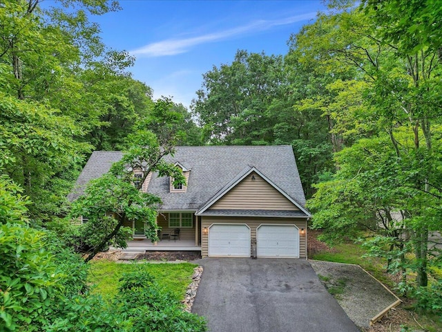 view of front of home featuring driveway, a shingled roof, a garage, and a porch