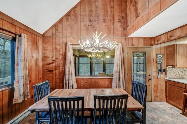 dining room featuring a baseboard radiator, wood walls, a notable chandelier, and lofted ceiling