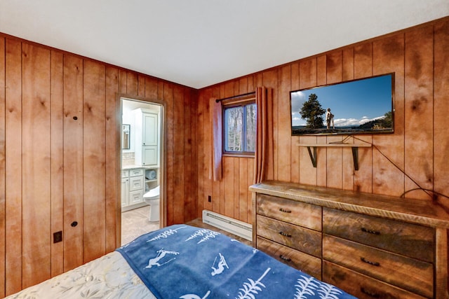 bedroom with wood walls, baseboard heating, and ensuite bath