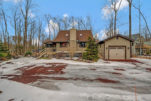 view of front facade featuring a garage, driveway, a shingled roof, and a chimney