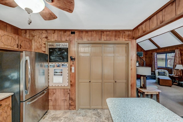 kitchen with ceiling fan, wood walls, vaulted ceiling, and freestanding refrigerator