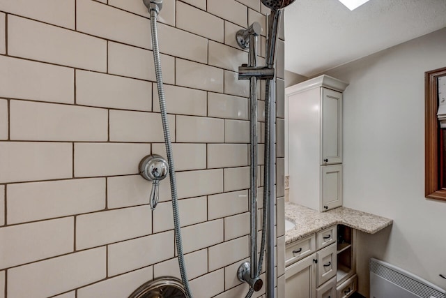 full bathroom featuring tiled shower, radiator heating unit, and vanity