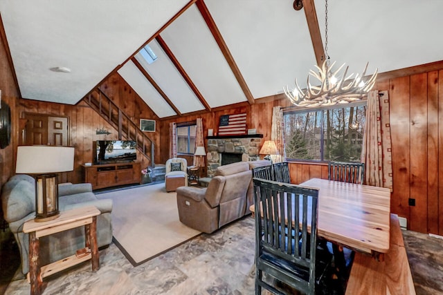 living room with a chandelier, a stone fireplace, high vaulted ceiling, and wooden walls