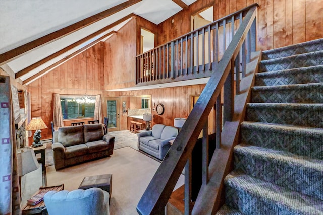 living room with high vaulted ceiling, beamed ceiling, wooden walls, and stairs