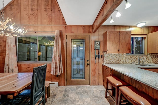 kitchen with light countertops, wood walls, a sink, and backsplash