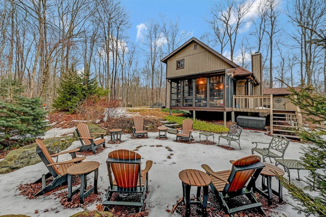 back of property with a fire pit, a patio, a sunroom, a chimney, and a wooden deck