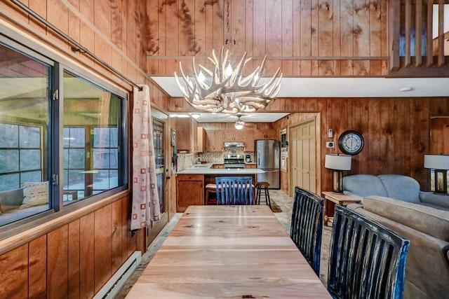 dining space with a baseboard radiator, a notable chandelier, and wood walls