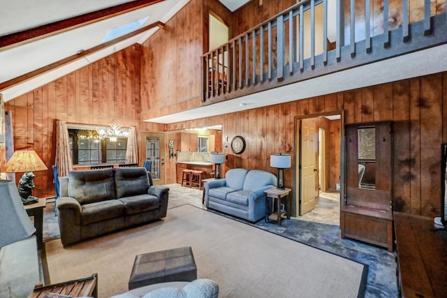 living room with high vaulted ceiling, wood walls, a skylight, and beamed ceiling