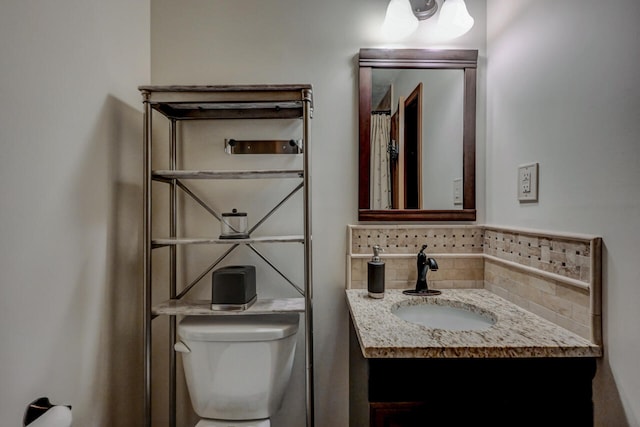 bathroom with vanity, backsplash, and toilet