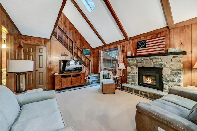 carpeted living room with lofted ceiling with beams, wood walls, stairs, and a stone fireplace