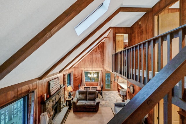 interior space with vaulted ceiling with skylight, a stone fireplace, and wooden walls