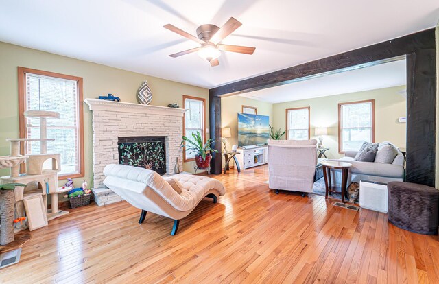 1154 Park Dr, East Stroudsburg, PA 18302 - living area featuring light wood-style flooring, a ceiling fan, a stone fireplace, and beamed ceiling