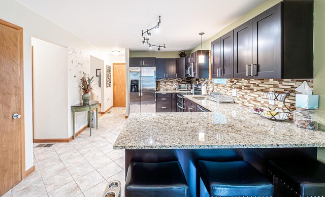 1154 Park Dr, East Stroudsburg, PA 18302 - kitchen featuring appliances with stainless steel finishes, light stone counters, a peninsula, backsplash, and light tile patterned floors