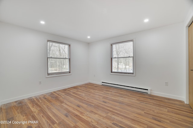 unfurnished room with plenty of natural light, a baseboard radiator, wood finished floors, and recessed lighting