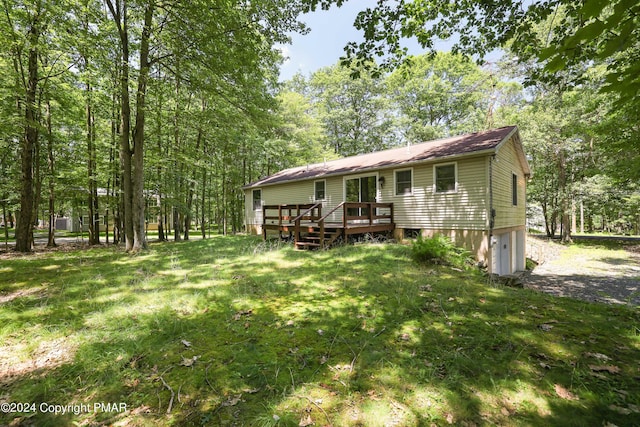 view of front of house featuring an attached garage, a front lawn, and a wooden deck