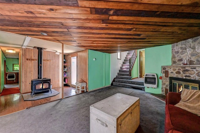 209 Cross St, Pocono Lake, PA 18347 - carpeted living room with heating unit, a wood stove, stairs, a stone fireplace, and wood ceiling