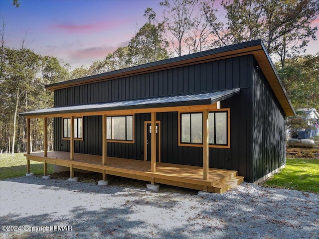 view of front facade with covered porch, metal roof, board and batten siding, and a standing seam roof