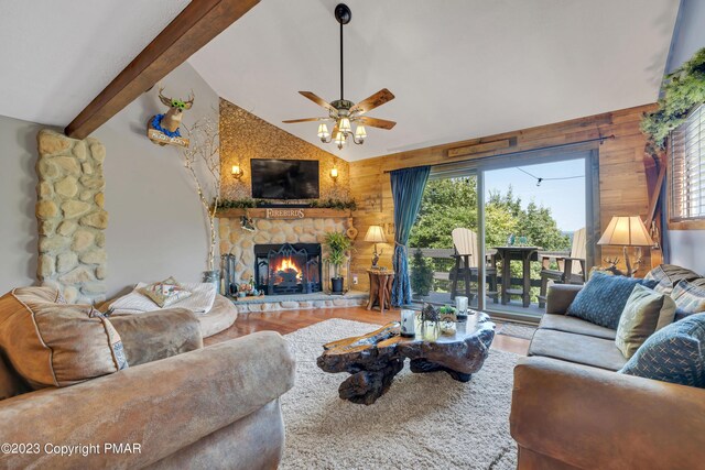 living room featuring lofted ceiling with beams, wood walls, a fireplace, and wood finished floors