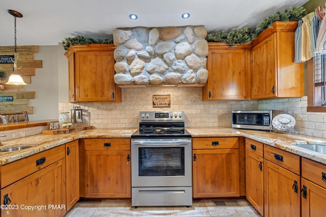 kitchen with appliances with stainless steel finishes, a sink, light stone counters, and tasteful backsplash