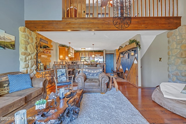 living area featuring beam ceiling, a towering ceiling, and hardwood / wood-style flooring