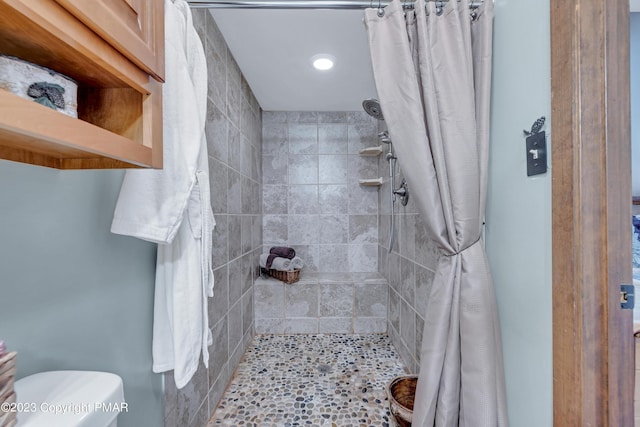 bathroom featuring a tile shower and toilet