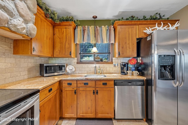 kitchen featuring stainless steel appliances, brown cabinetry, a sink, and decorative backsplash