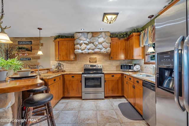 kitchen with a peninsula, appliances with stainless steel finishes, decorative backsplash, and a sink