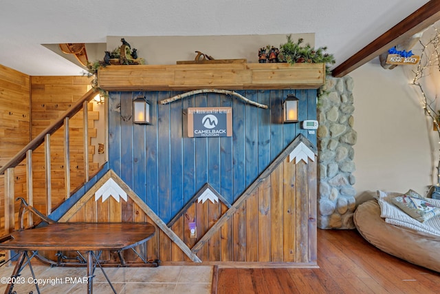 details featuring a textured ceiling, beamed ceiling, wood finished floors, and wooden walls