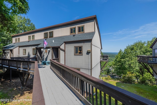 rear view of property with a shingled roof and a deck