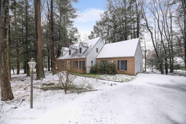 cape cod house featuring brick siding