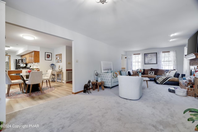 living room featuring a baseboard heating unit, light colored carpet, and baseboards