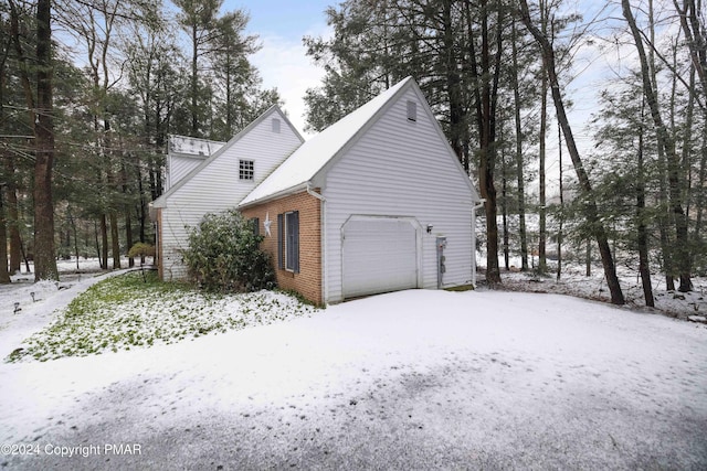 snow covered property with brick siding and an attached garage