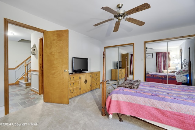 bedroom with ceiling fan, carpet, and multiple closets