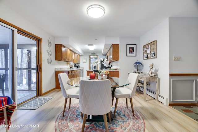 dining space featuring a baseboard heating unit and light wood finished floors