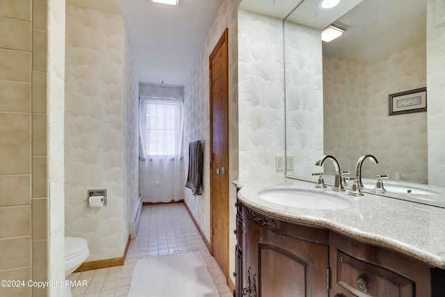 bathroom with toilet, wallpapered walls, tile patterned flooring, and vanity