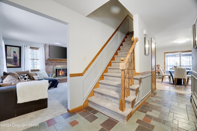 stairway with stone tile floors, a fireplace, baseboards, and baseboard heating