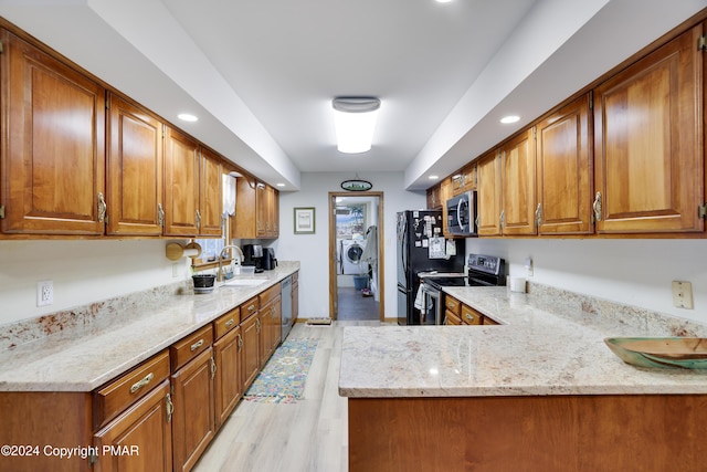 kitchen with appliances with stainless steel finishes, brown cabinetry, and a sink