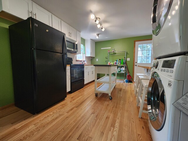 9 Theocritus Cir, Albrightsville, PA 18210 - kitchen featuring black appliances, stacked washer and clothes dryer, white cabinets, light wood-type flooring, and plenty of natural light