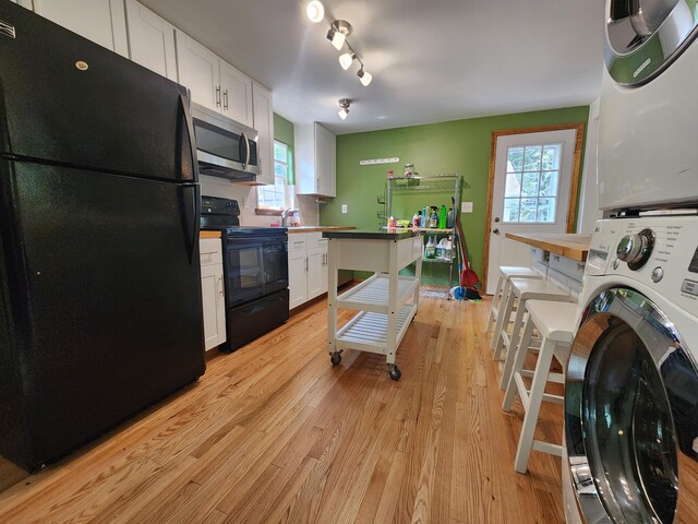 9 Theocritus Cir, Albrightsville, PA 18210 - kitchen with black appliances, stacked washer / dryer, light wood-style floors, white cabinets, and healthy amount of natural light